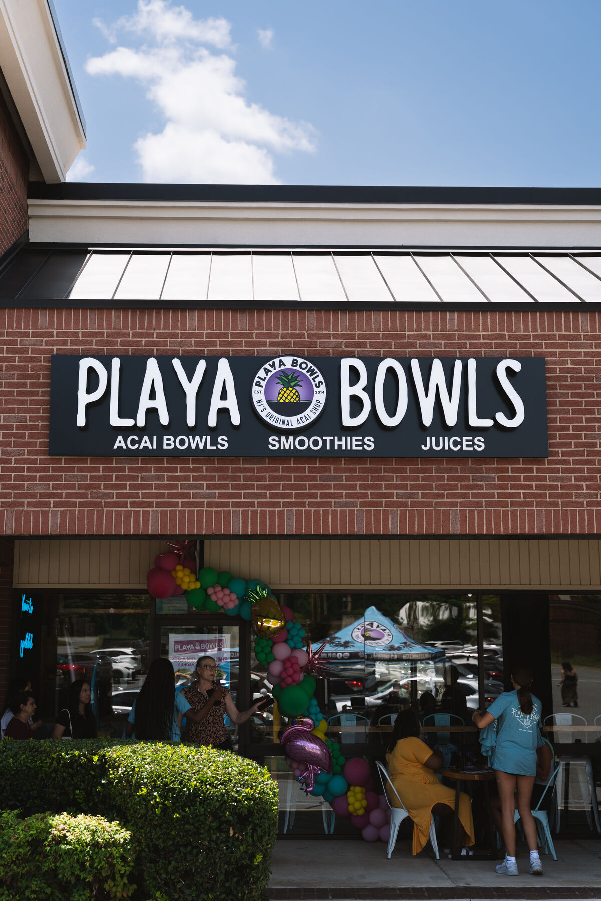 Playa Bowls interior — staff preparing fresh bowls behind the counter with colorful menu boards